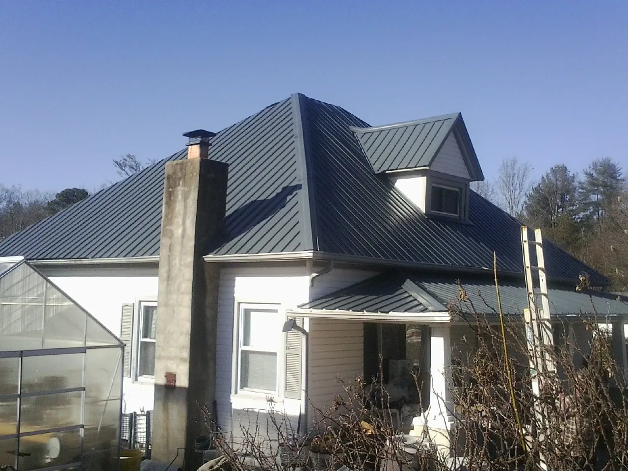 Dark blue standing seam metal roof on a white farmhouse with dormer — Slate & Tile Roof Repair by Roofing Brothers in Pillsbury