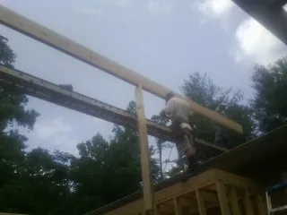 Carpenter setting a ridge beam over a new addition frame — Ice Dam Removal by Roofing Brothers in Pillsbury