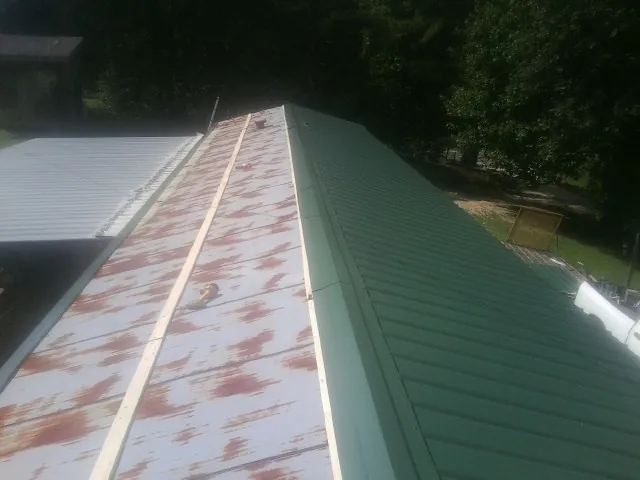 Old rusted panels beside newly installed green metal roofing — Wind Damage Roof Repair by Roofing Brothers in Pillsbury