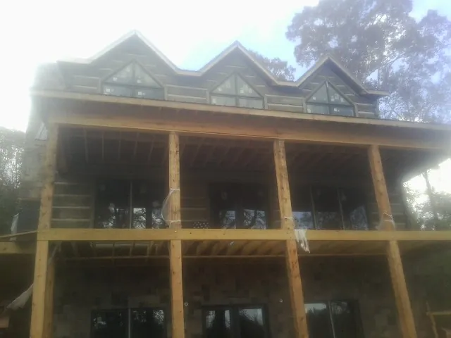 Dormers and porch framing on a large log home under construction — Roof Coating work by our crew in Pillsbury