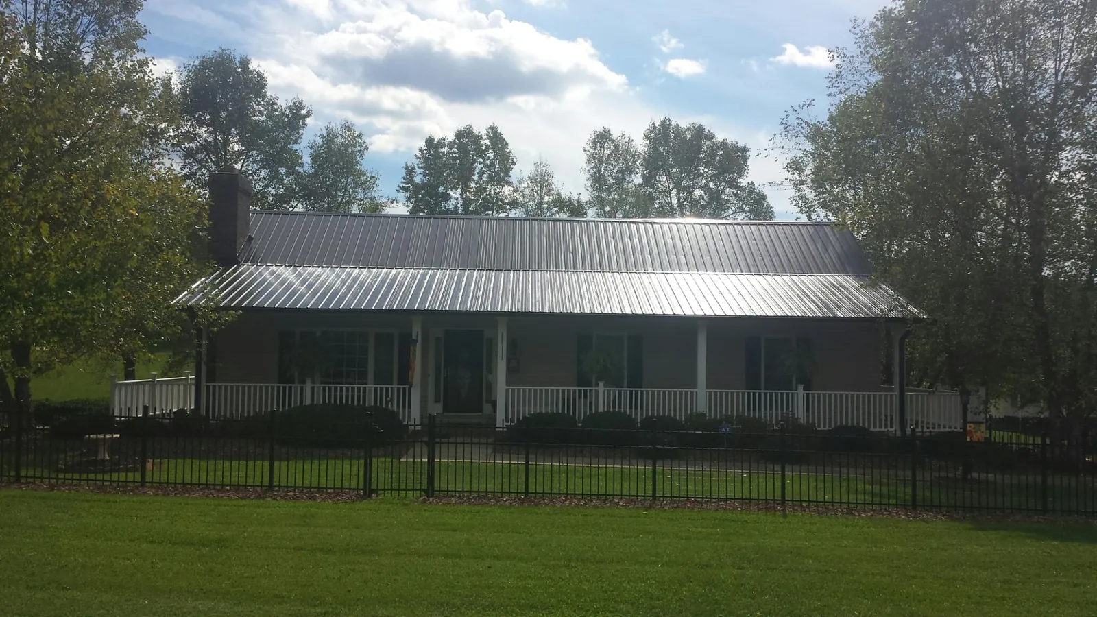 Gray metal roof on a brick ranch with a full width front porch — Gutter Guard Installation work by our crew in Pillsbury