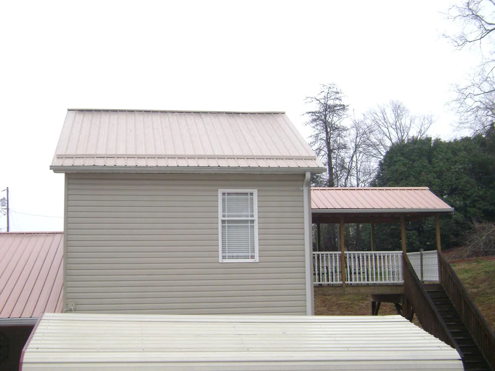 Tan metal roofs on a two story addition and attached porch, from a Roof Replacement job in Pillsbury
