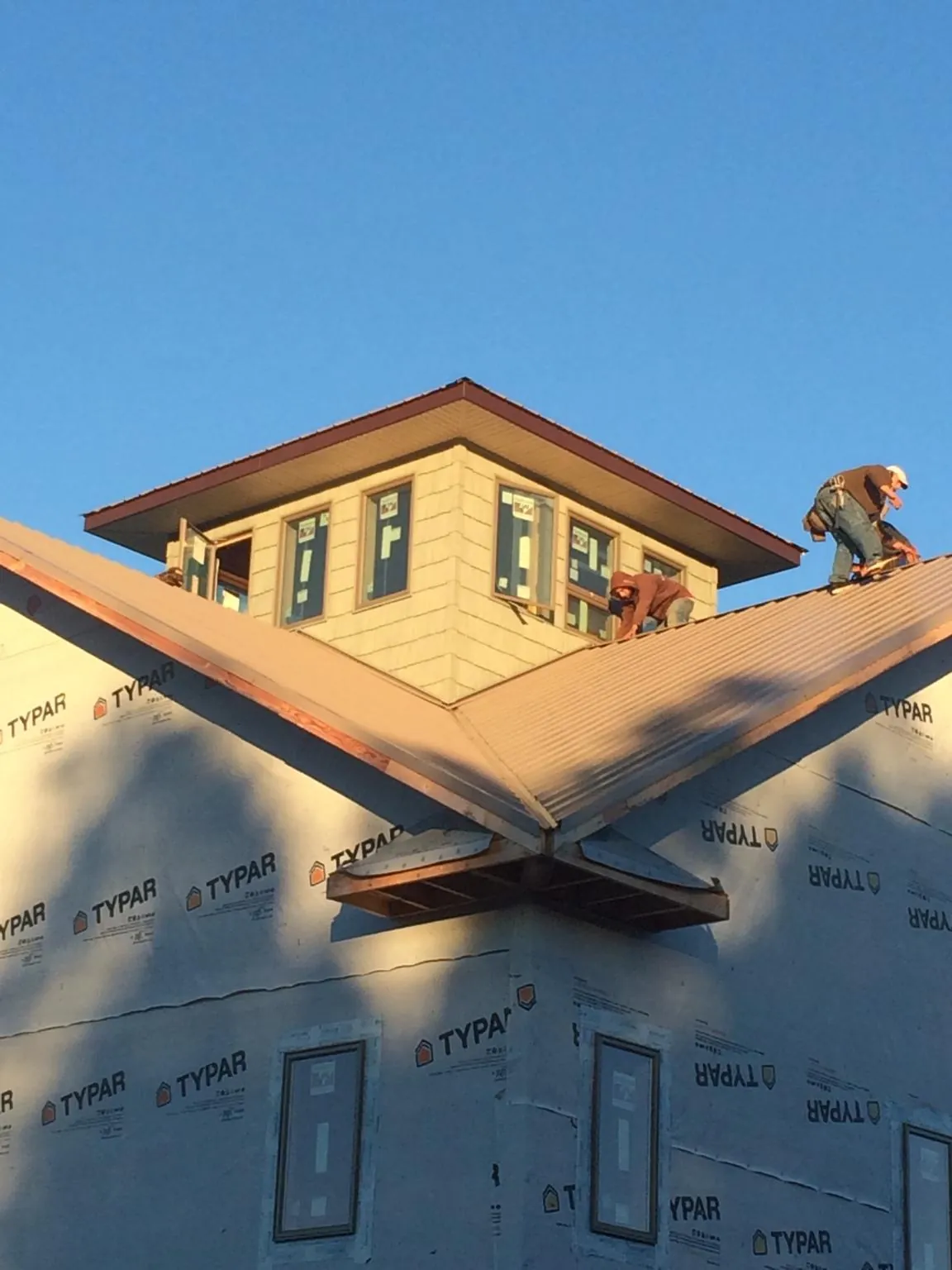 Roofers working around a rooftop cupola on a new metal roof at sunset — Roof Waterproofing in Pillsbury by Roofing Brothers